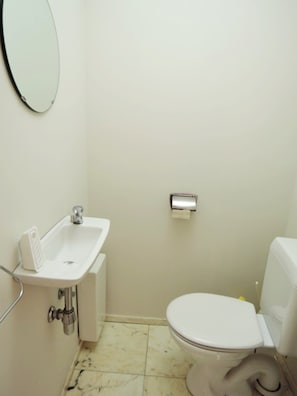 A small, clean bathroom with a white sink, toilet, and a mirror on the wall. - Apartment in Middelkerke With Sea Views (Middelkerke)