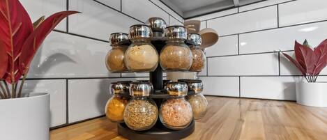 A spice rack with multiple glass jars on a rotating stand in a kitchen.