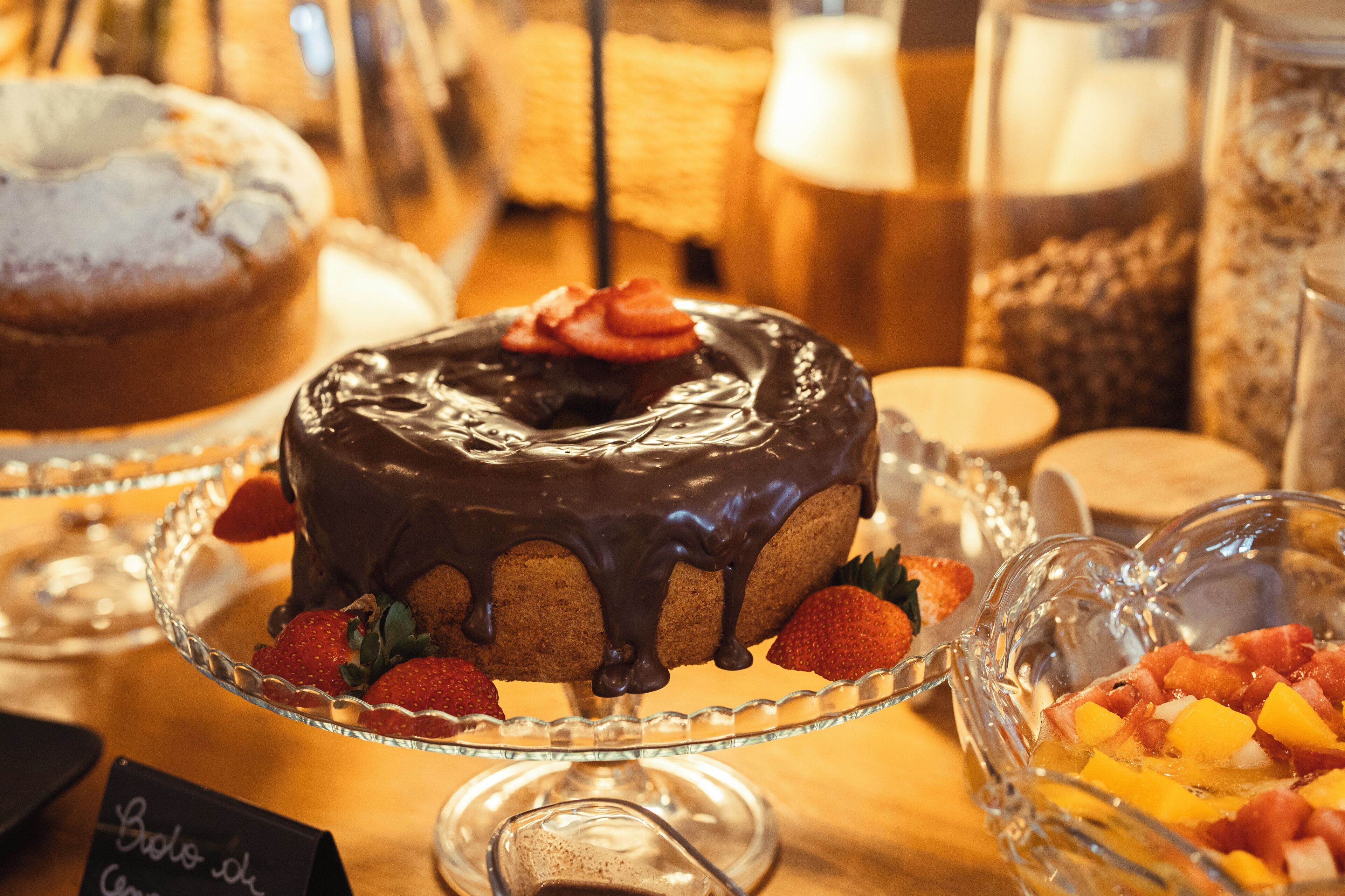 Ein Kuchen mit Schokoladenglasur und Erdbeeren auf einer Glasplatte.