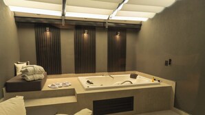 Un baño moderno con una bañera independiente, una zona de estar con un banco acolchado y un tragaluz grande.