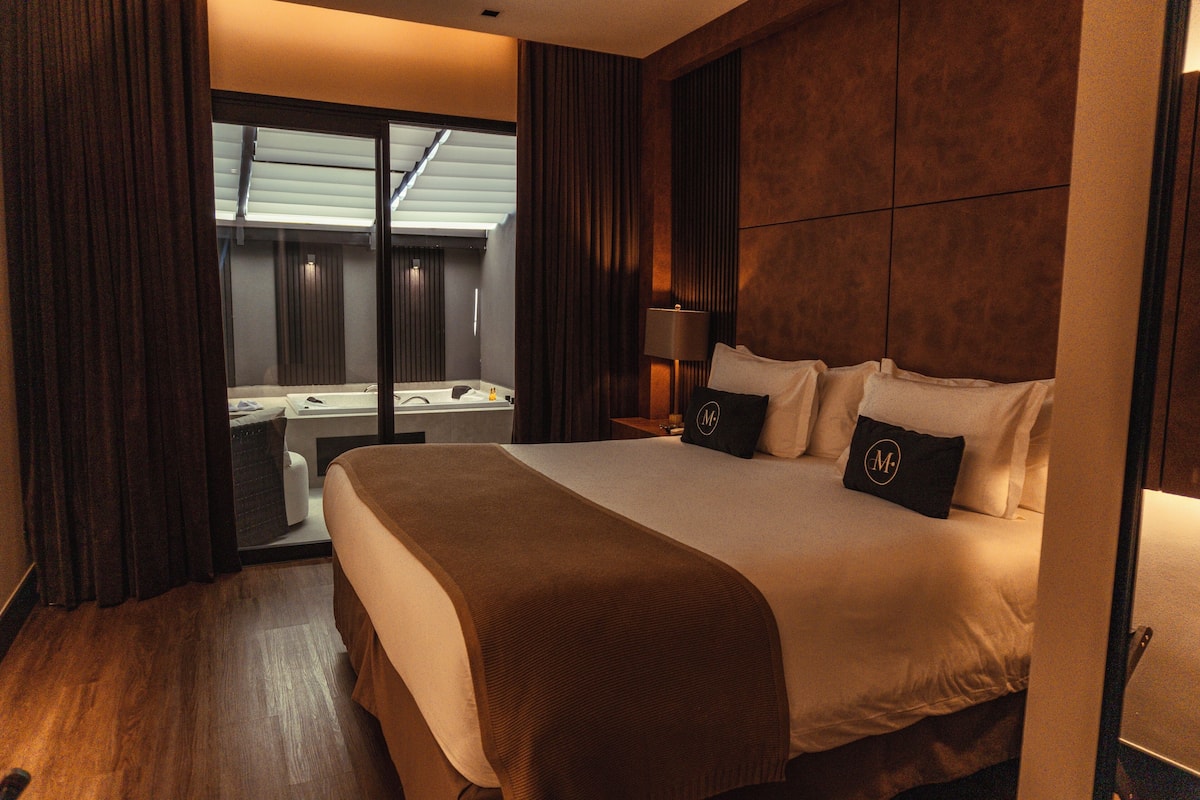 Ein Hotelzimmer mit einem großen Bett, einem Schreibtisch mit Stuhl, einem Fenster mit Vorhängen und Blick auf einen Pool.