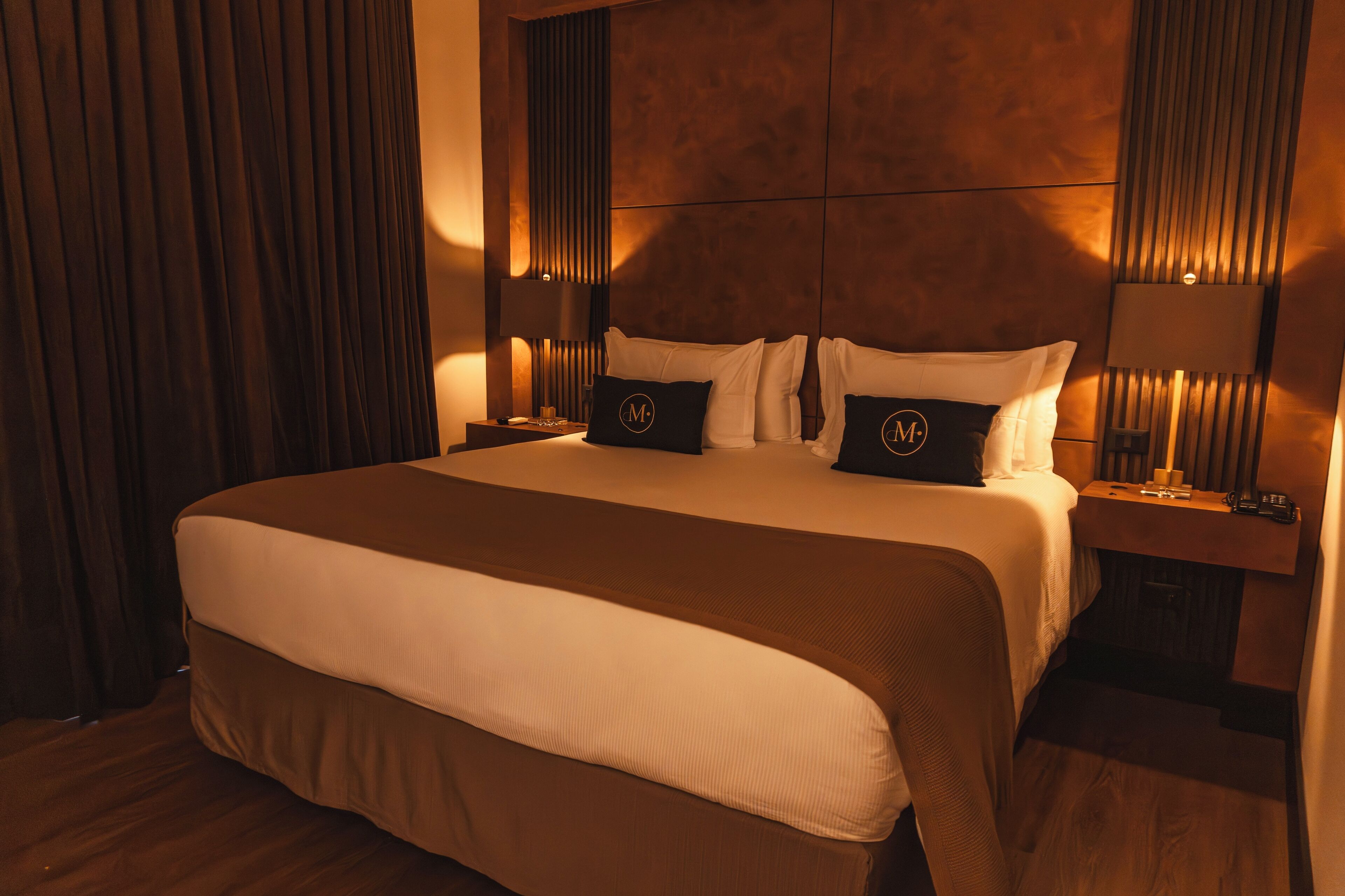 A large bed with a headboard, two bedside tables, and a nightstand.
