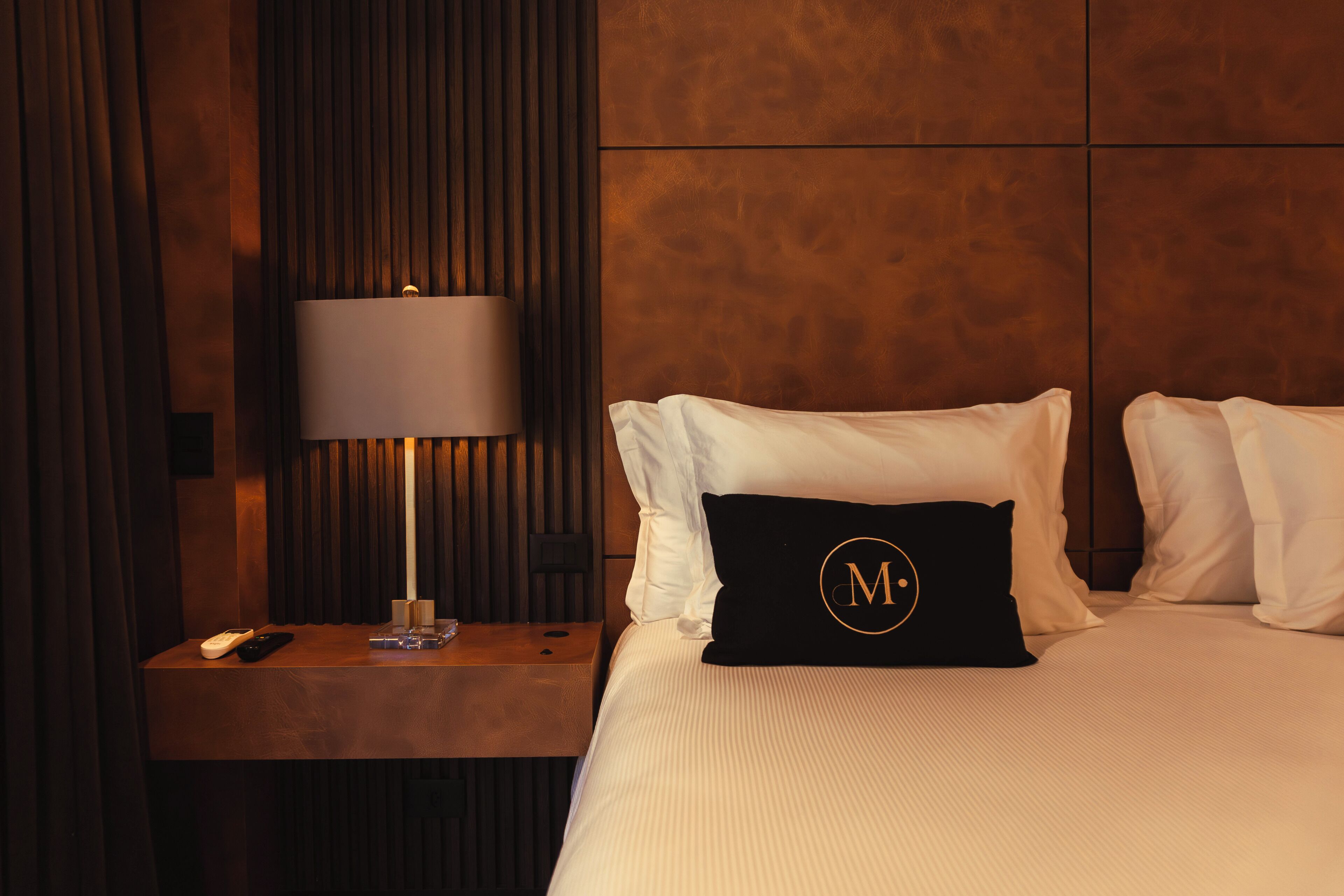 Une chambre d’hôtel avec un lit, une table de chevet, une lampe et une télécommande.