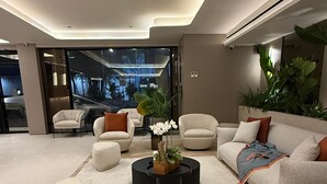 Een moderne woonkamer met een bank, fauteuils, een salontafel en een potplant.