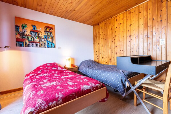 A bedroom with a bed, a desk, and a chair.
