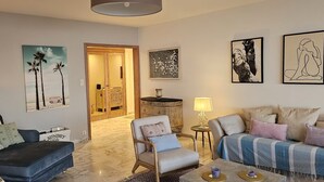 A living room with a sofa, armchair, and coffee table, a side table with a lamp, and artwork on the walls. - Dream apartment with sea view (Cannes)