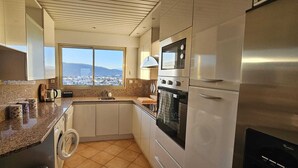 A modern kitchen with granite countertops, stainless steel appliances, and a view of a cityscape through a large window. - Dream apartment with sea view (Cannes)
