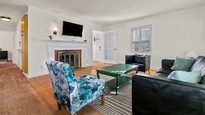A living room with a fireplace, a television mounted on the wall, and a sofa.