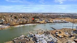 An aerial view of a marina with boats docked, a river, and surrounding residential areas.
