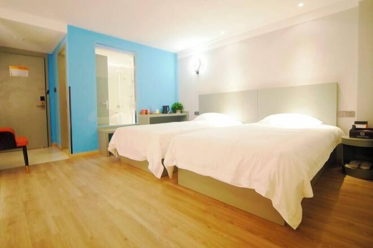 Une chambre d’hôtel moderne avec un grand lit, une table de chevet, une chaise et un mur d’accent bleu.