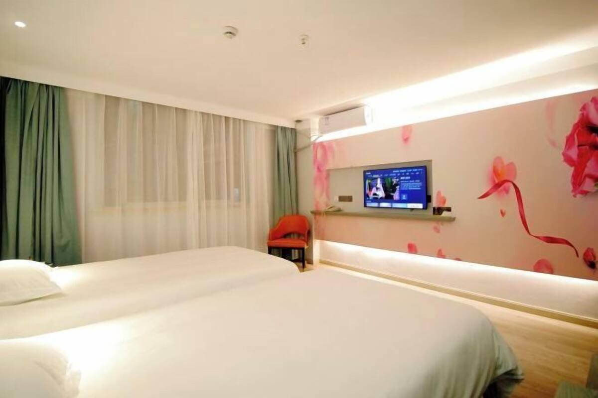 Une chambre d’hôtel avec deux lits, une télévision et un bureau avec une chaise.
