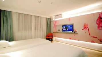 A hotel room with two beds, a television, and a desk with a chair.