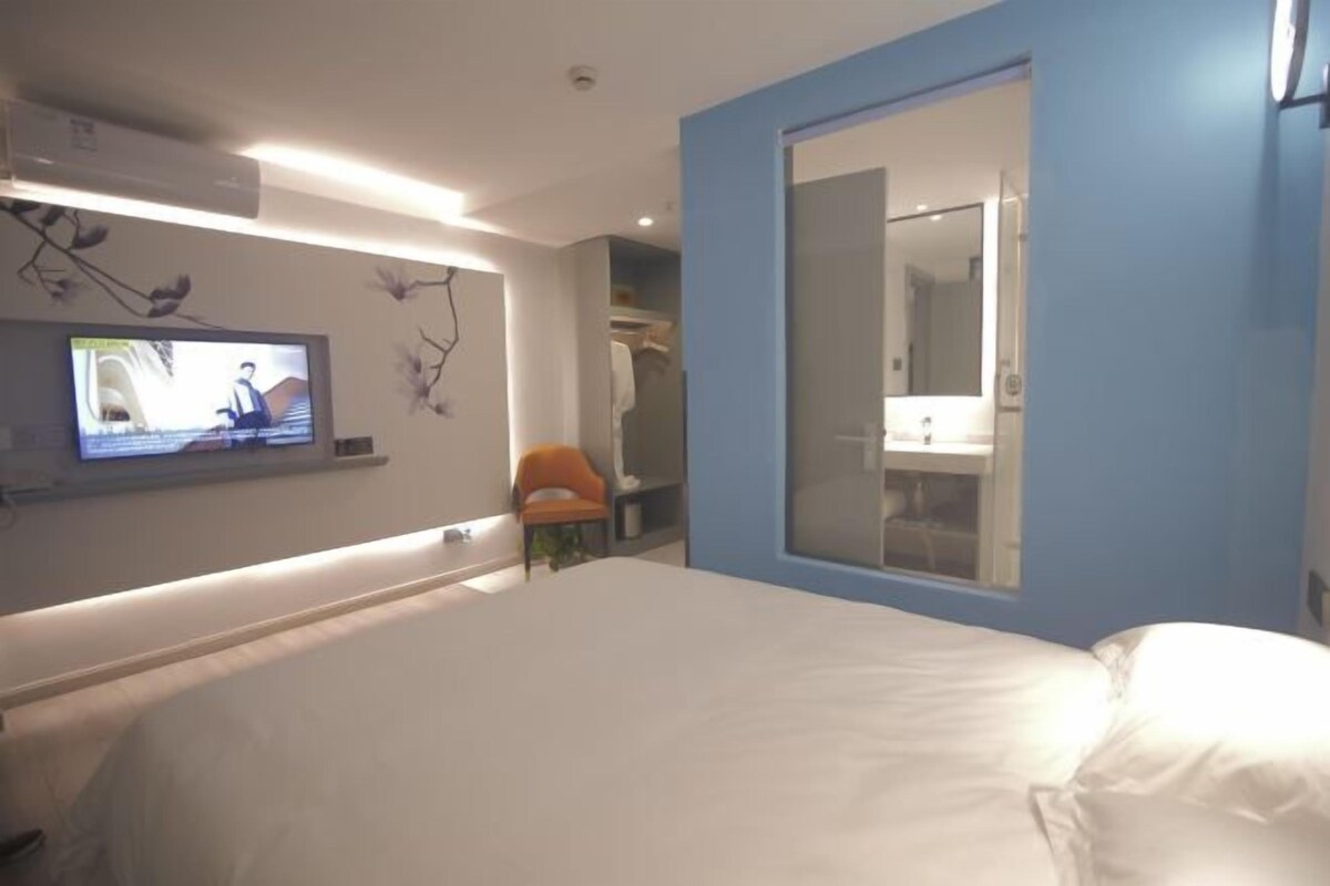 Une chambre d’hôtel moderne avec un grand lit, un téléviseur fixé au mur et un placard à portes coulissantes.