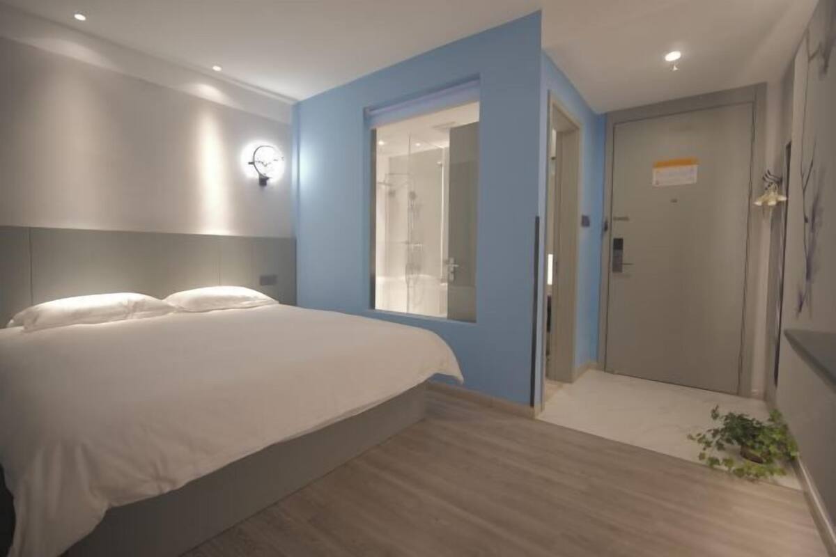 Une chambre à coucher avec un lit, un mur d’accent bleu, une cabine de douche en verre et une porte avec une pancarte.