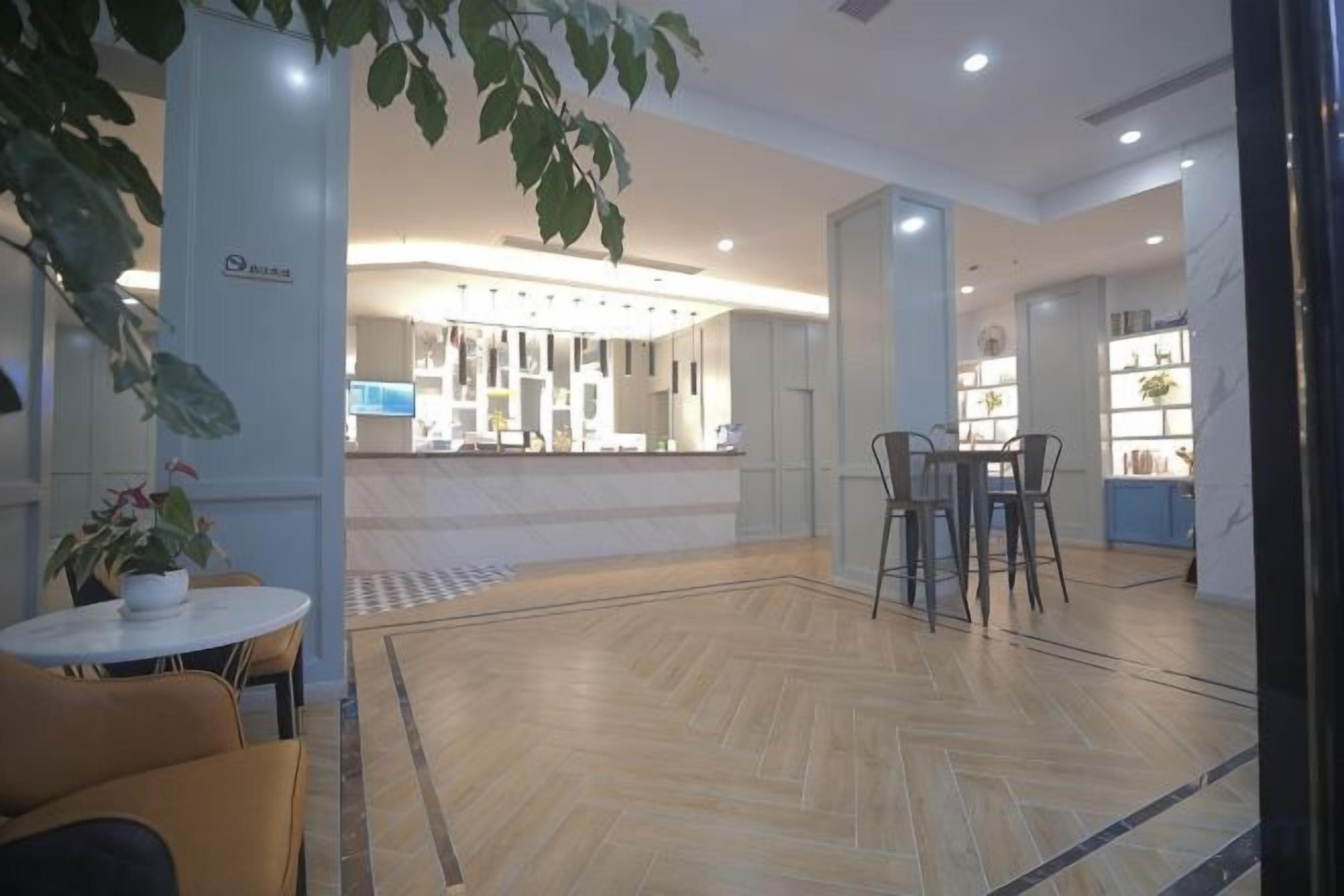 A hotel lobby with a reception desk, seating area, and a plant.