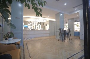 Un vestíbulo de hotel con mostrador de recepción, zona de estar y una planta.