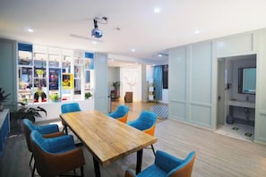 A modern dining area with a wooden table and blue chairs, a television, and a visible kitchen area. - Jinhuangchao Light extravagance Hotel (Shanghai)