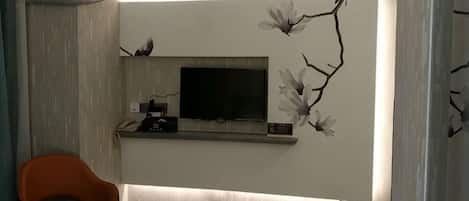 A modern living room with a flat-screen TV, a comfortable chair, and decorative wall art.