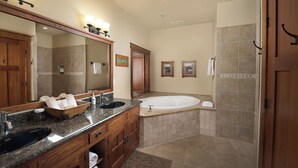 Un baño con un espejo grande, un lavamanos, una bañera y una ducha.