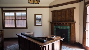 Una sala de estar con un banco de madera, una chimenea y un ventanal con persianas.