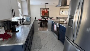 A modern kitchen with a large island, stainless steel appliances, and a dining area with a red floral painting. - Paradise Lake (Clearwater)