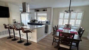 A modern kitchen with a central island, bar stools, and a dining area with a table and chairs. - Paradise Lake (Clearwater)