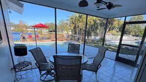 A sunlit patio with a pool, outdoor seating, and a ceiling fan. - Paradise Lake (Clearwater)