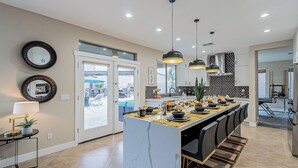 Een moderne keuken met een centraal eiland, hanglampen en uitzicht op het buitenteras.