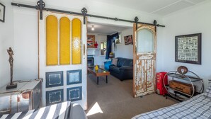 A room with a sliding door, a couch, a bed, and a vintage suitcase.