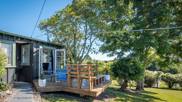 A wooden deck with outdoor seating, a covered patio area, and a view of a lush green landscape.