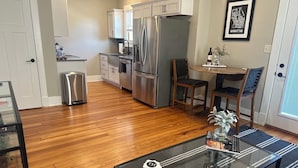 Una cocina moderna con electrodomésticos de acero inoxidable, un comedor con mesa de vidrio y un mapa de Manhattan enmarcado en la pared.