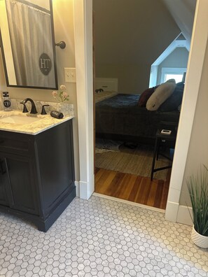A modern bathroom with a marble sink, black faucets, and a mirror with a towel hanging on it. - Thompson House #3-Overlooking City Park. Walk to Campus, Aggieville & Downtown (Manhattan)