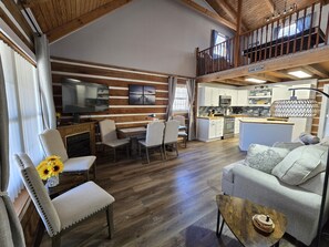 A spacious living area with a dining table, comfortable seating, a kitchen, and a balcony. - 20% OFF Escape to the Lake, Lake, Dock, Boat Ramp, Hot Tub, Game Room (Dandridge)