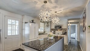 A modern kitchen with white cabinetry, granite countertops, and a central island. - Spacious Pool House – 5 Minutes to Elgin Centre (St. Thomas)