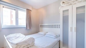 A single bed with white bedding, a white wardrobe with glass doors, and a window with curtains. - Apartment in Middelkerke With Sea View (Middelkerke)