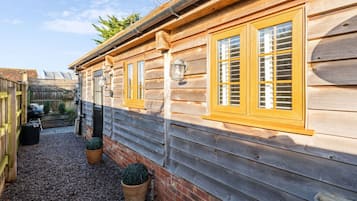 Traditional cabin with a rustic charm, featuring large windows and a gravel pathway.