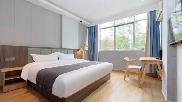 Une chambre d’hôtel moderne avec un grand lit, une table de chevet en bois, un bureau et une chaise.