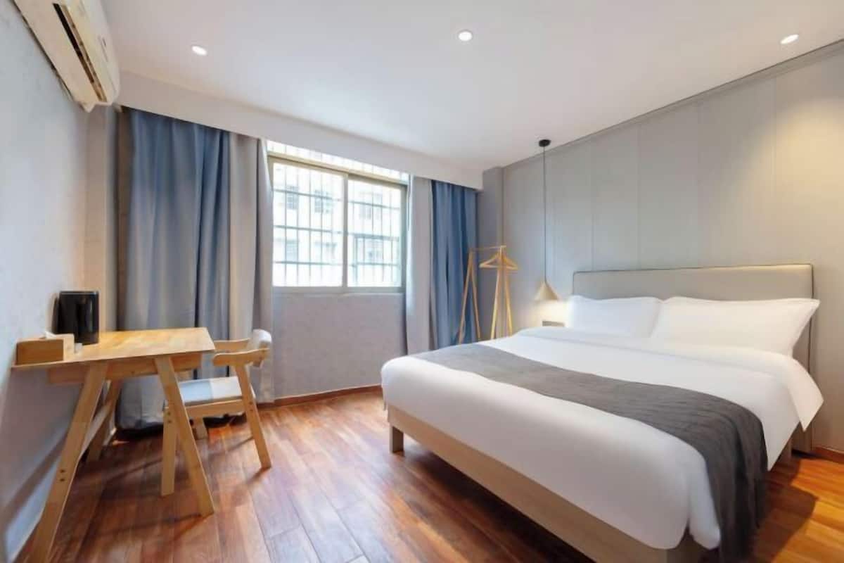 Una habitación de hotel con una cama, un escritorio, una silla, una lámpara y una ventana.