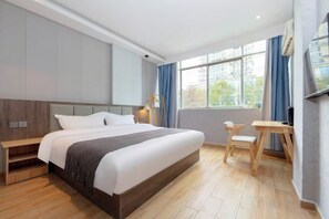 Una habitación de hotel moderna con una cama grande, una mesita de noche y un escritorio con una silla.