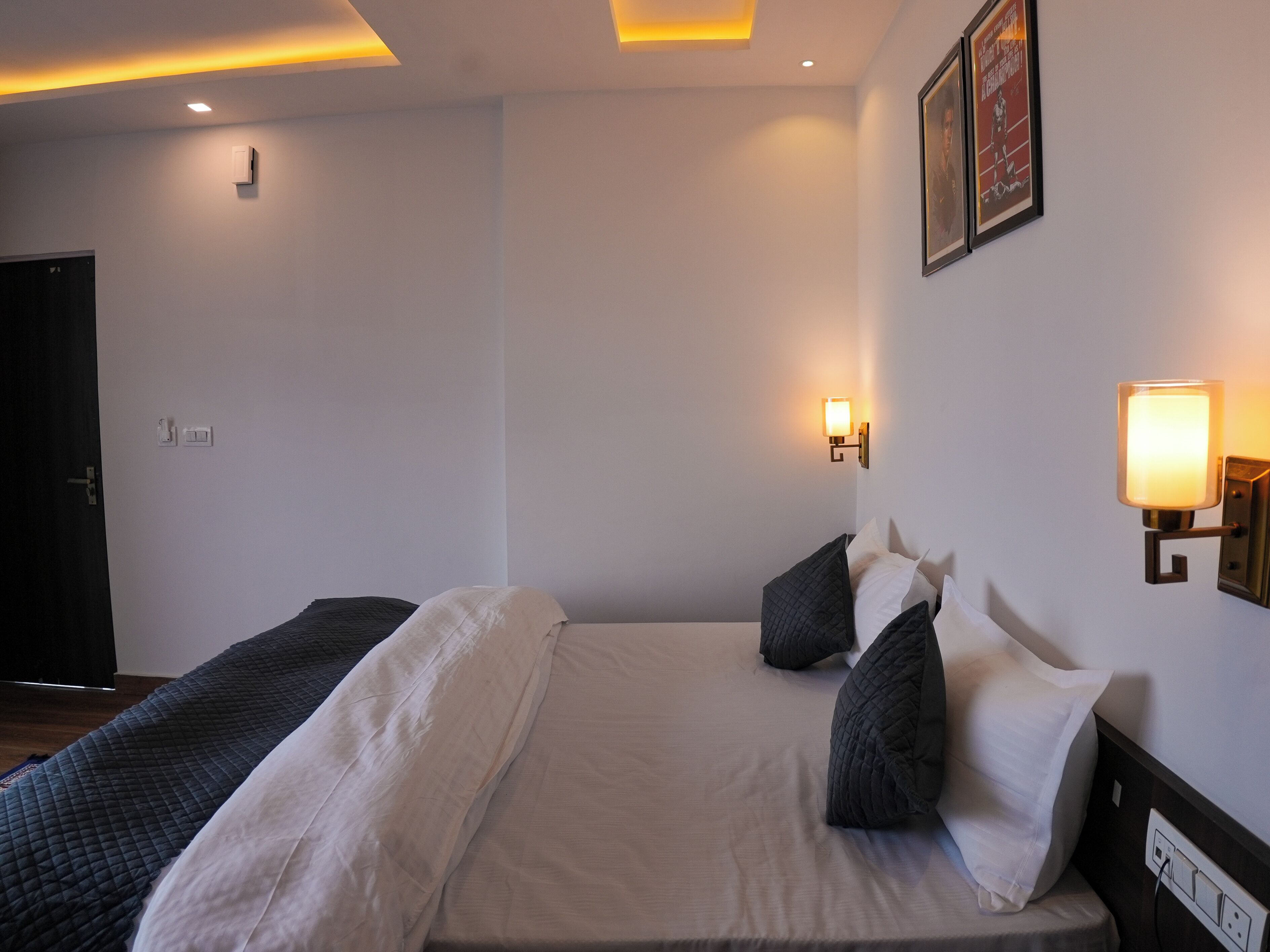A hotel room with a bed, two bedside tables, a wall-mounted light, and a door.