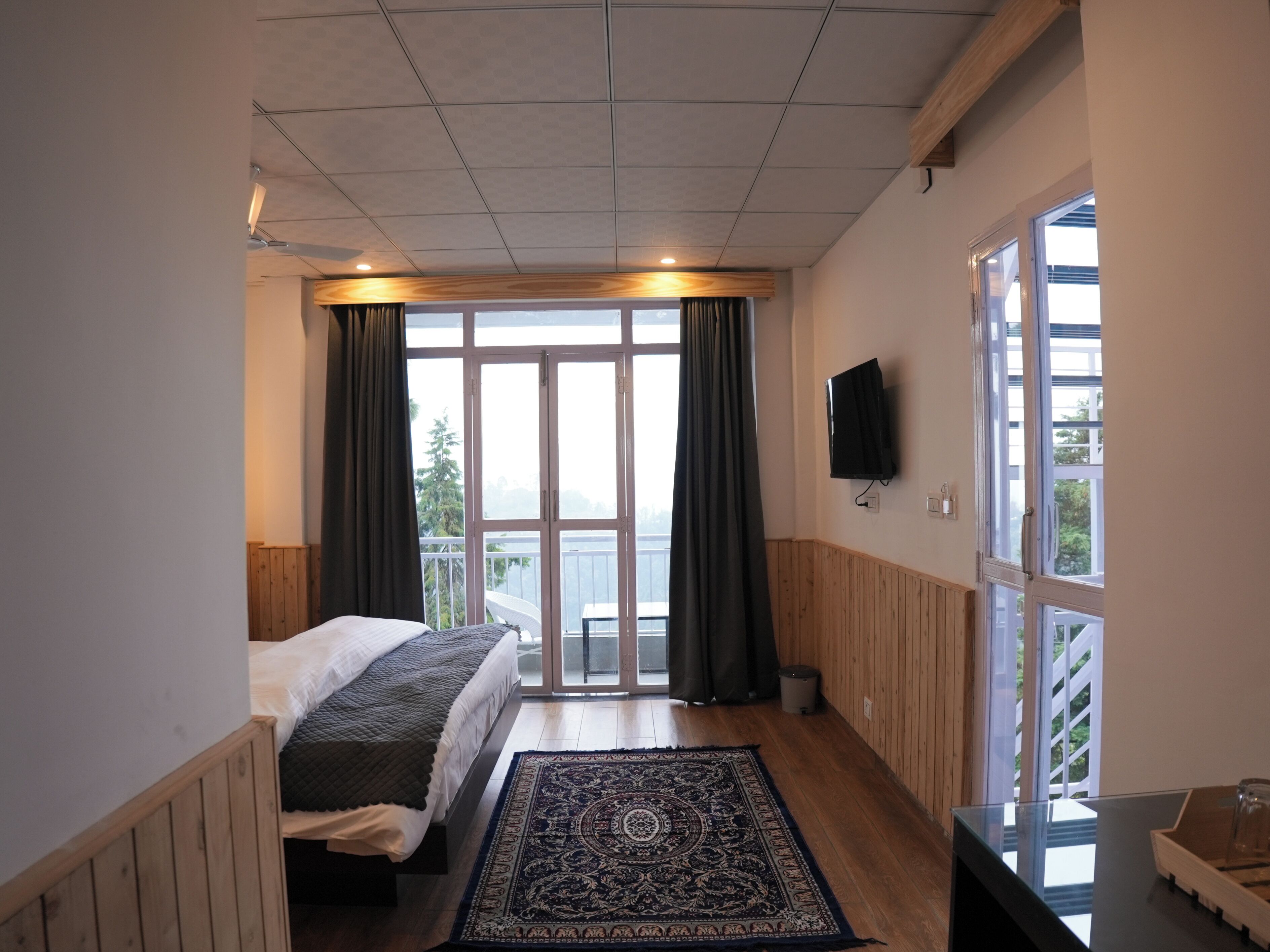 Une chambre à coucher avec un lit, une télévision, une grande fenêtre et une vue sur l’extérieur.