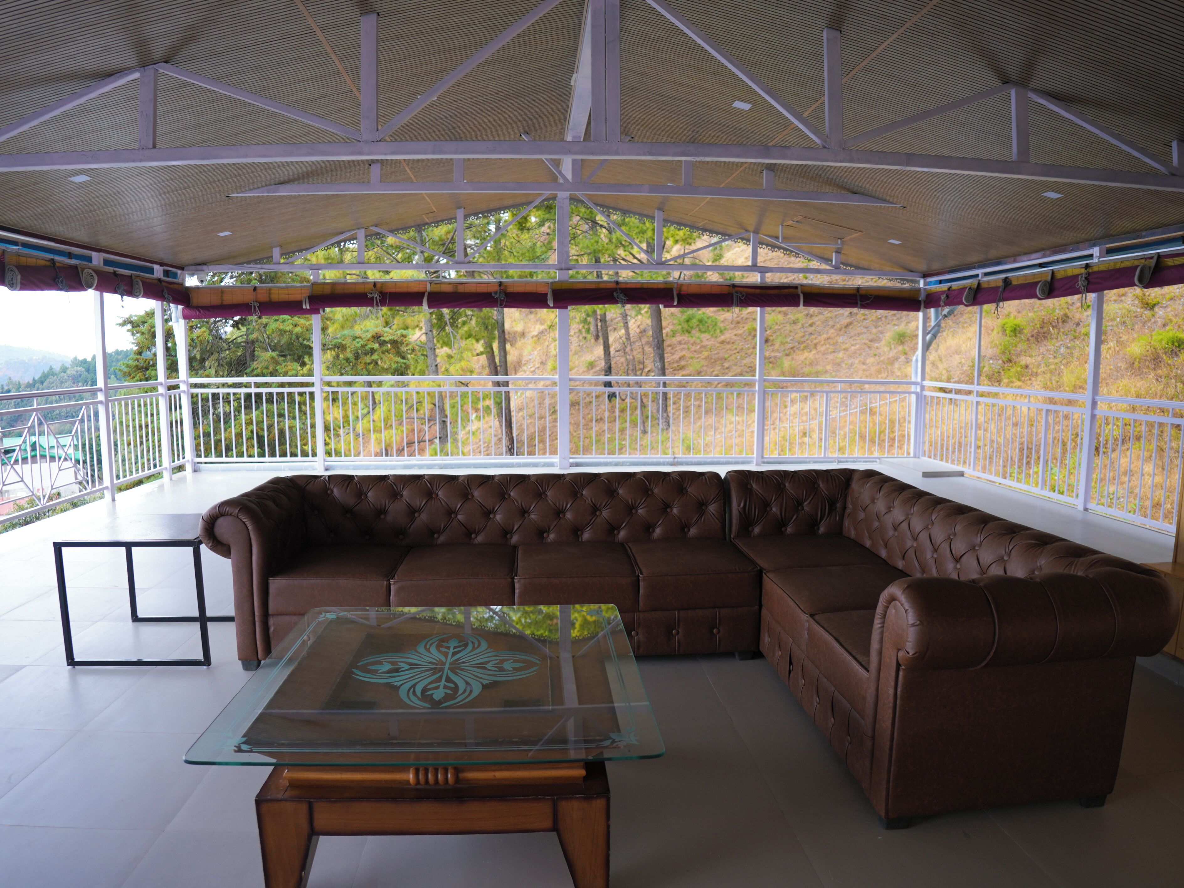 A spacious balcony with a leather sectional sofa and a glass coffee table.