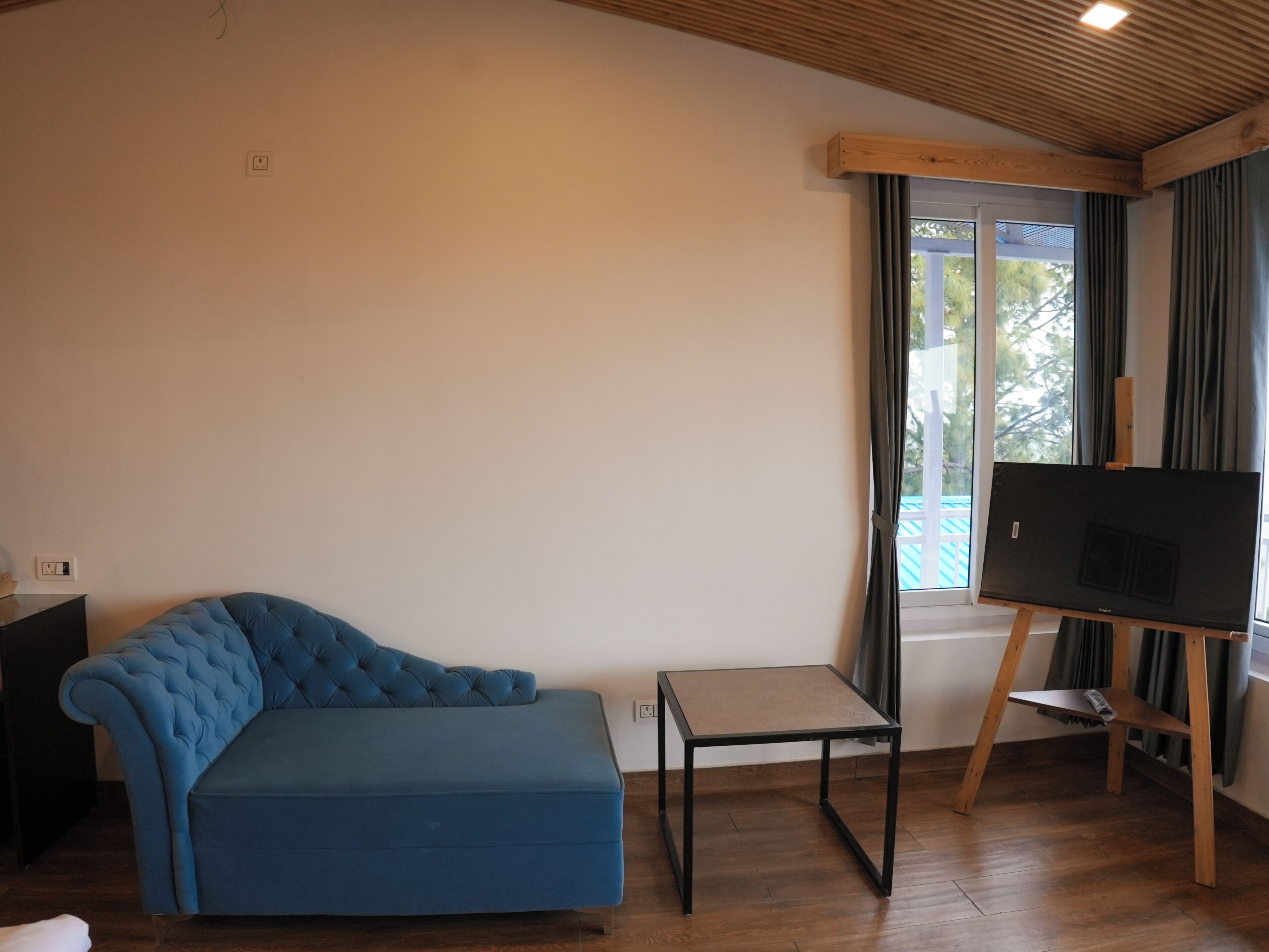 A room with a blue sofa, a small table, and a painting on an easel.