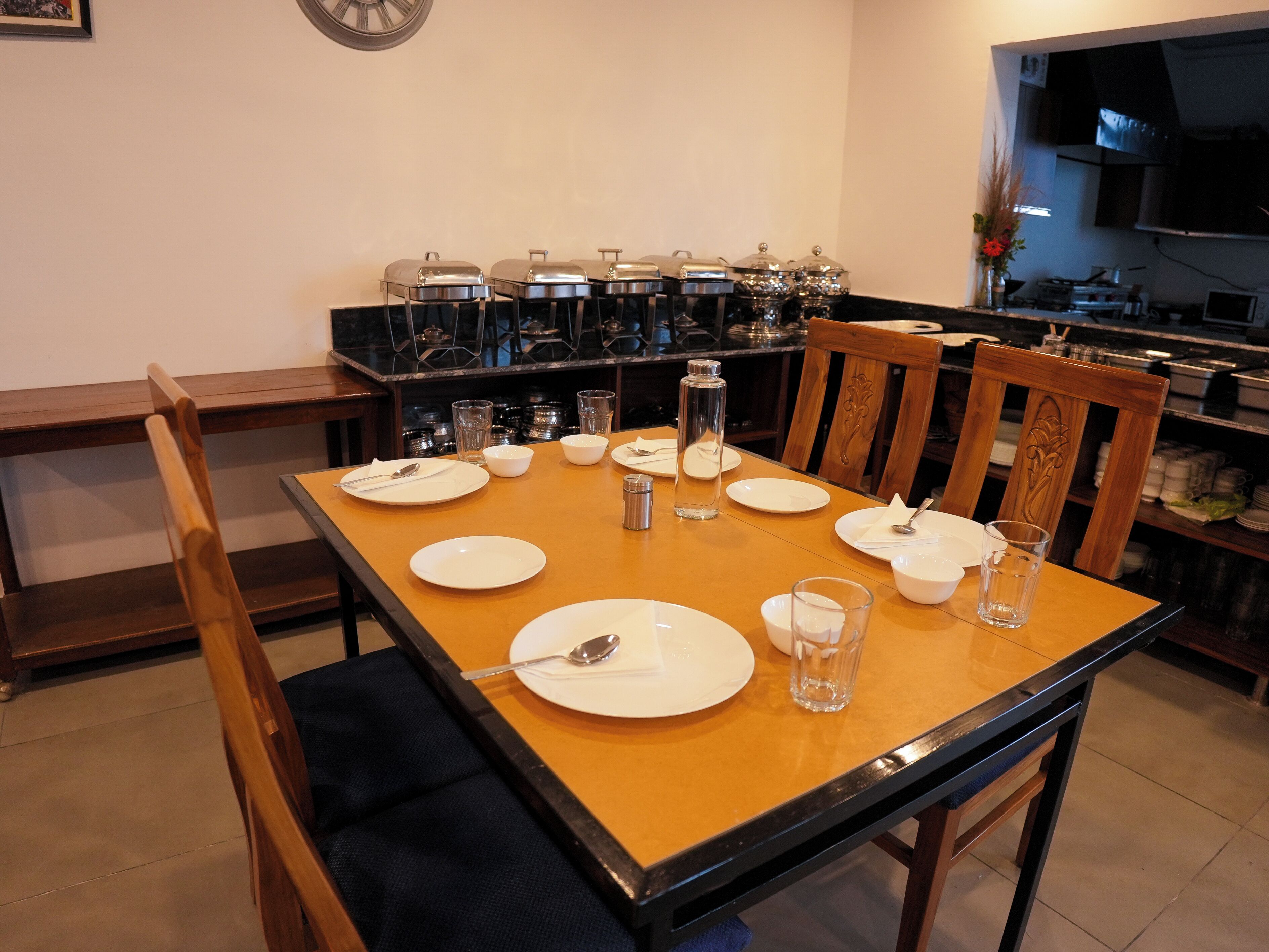 A dining table set with plates, bowls, and glasses, surrounded by chairs.
