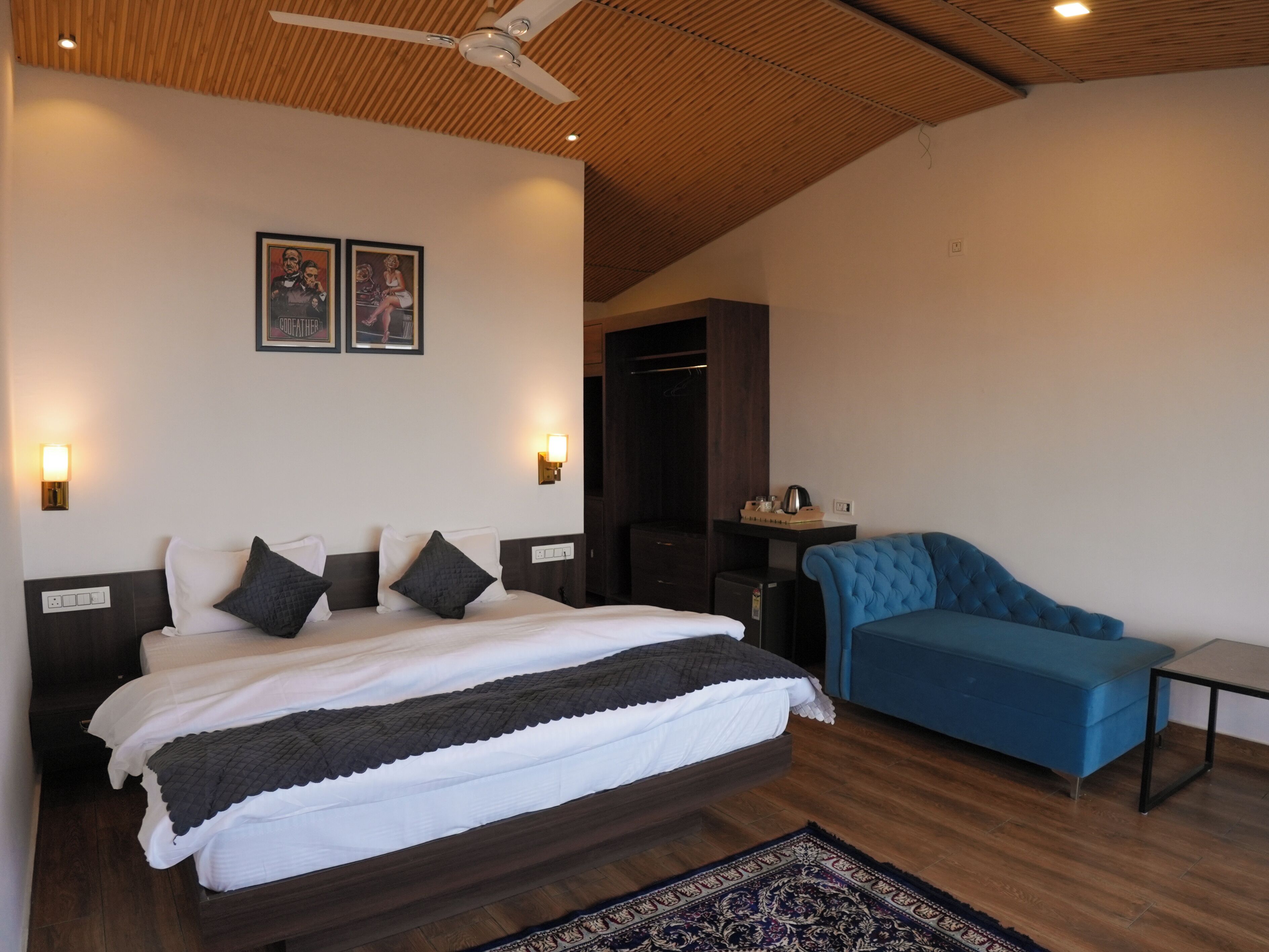 Un dormitorio moderno con una cama grande, un sofá azul y un ventilador de techo.