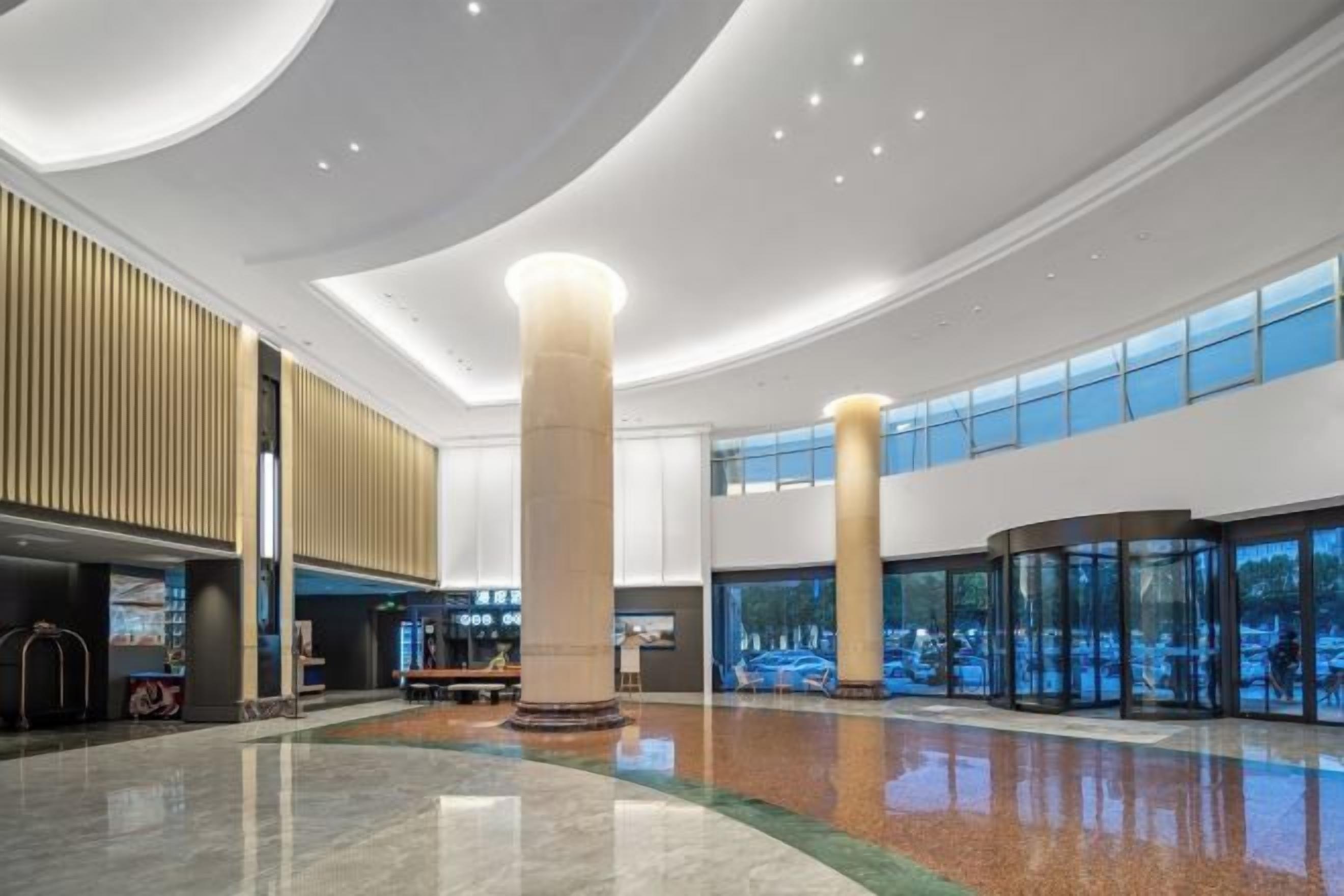 A spacious lobby with a high ceiling, large pillars, and a central seating area.