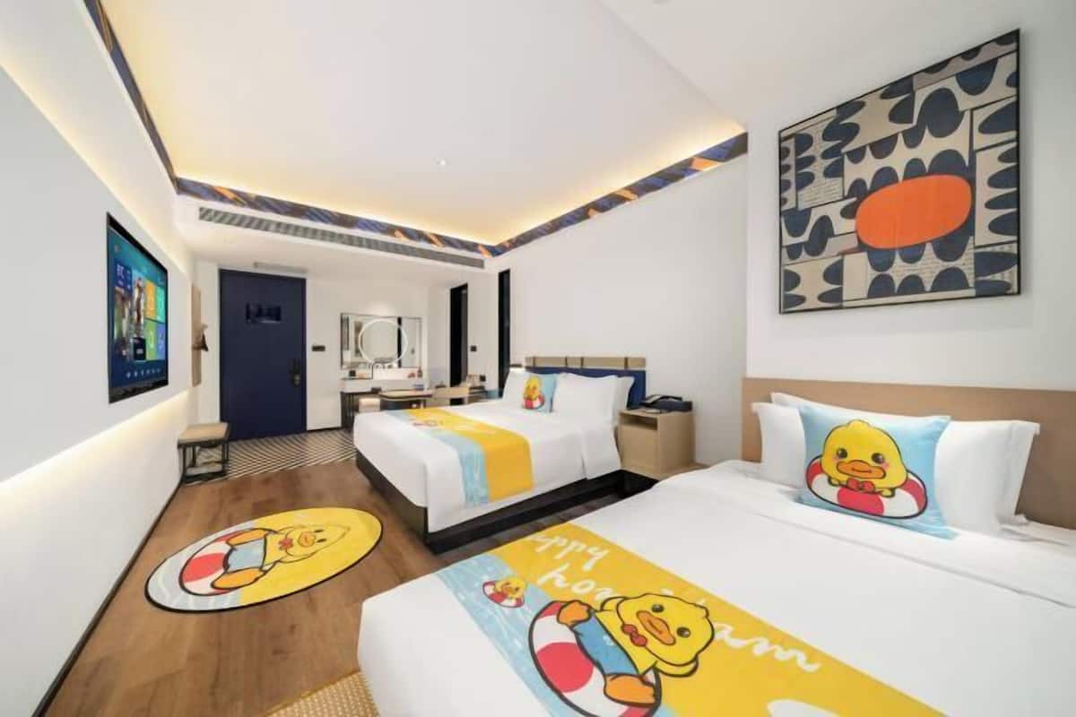A hotel room with two beds, a large artwork on the wall, and a TV on the wall.