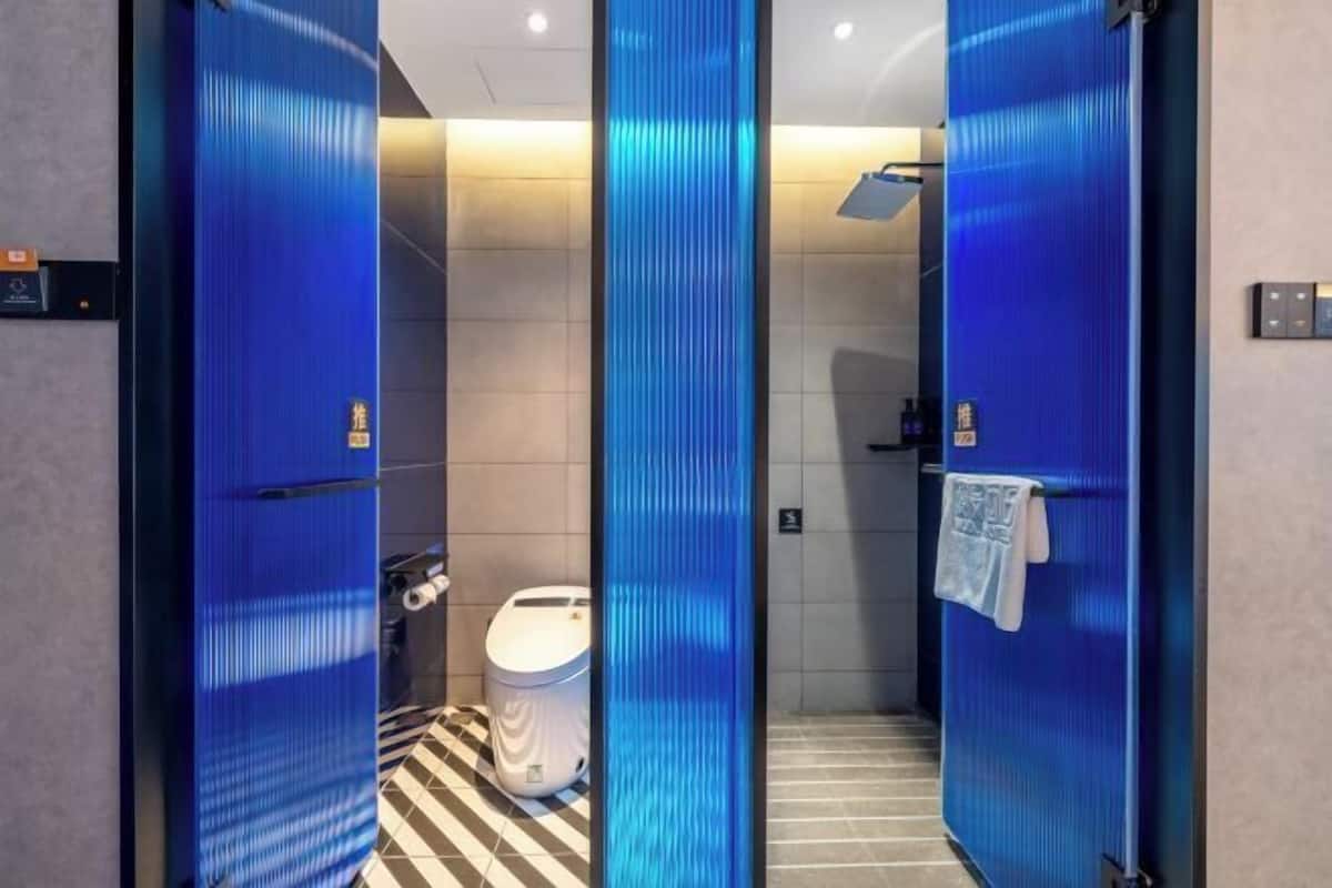 A modern bathroom with a striped floor, a white toilet, and a blue wall.