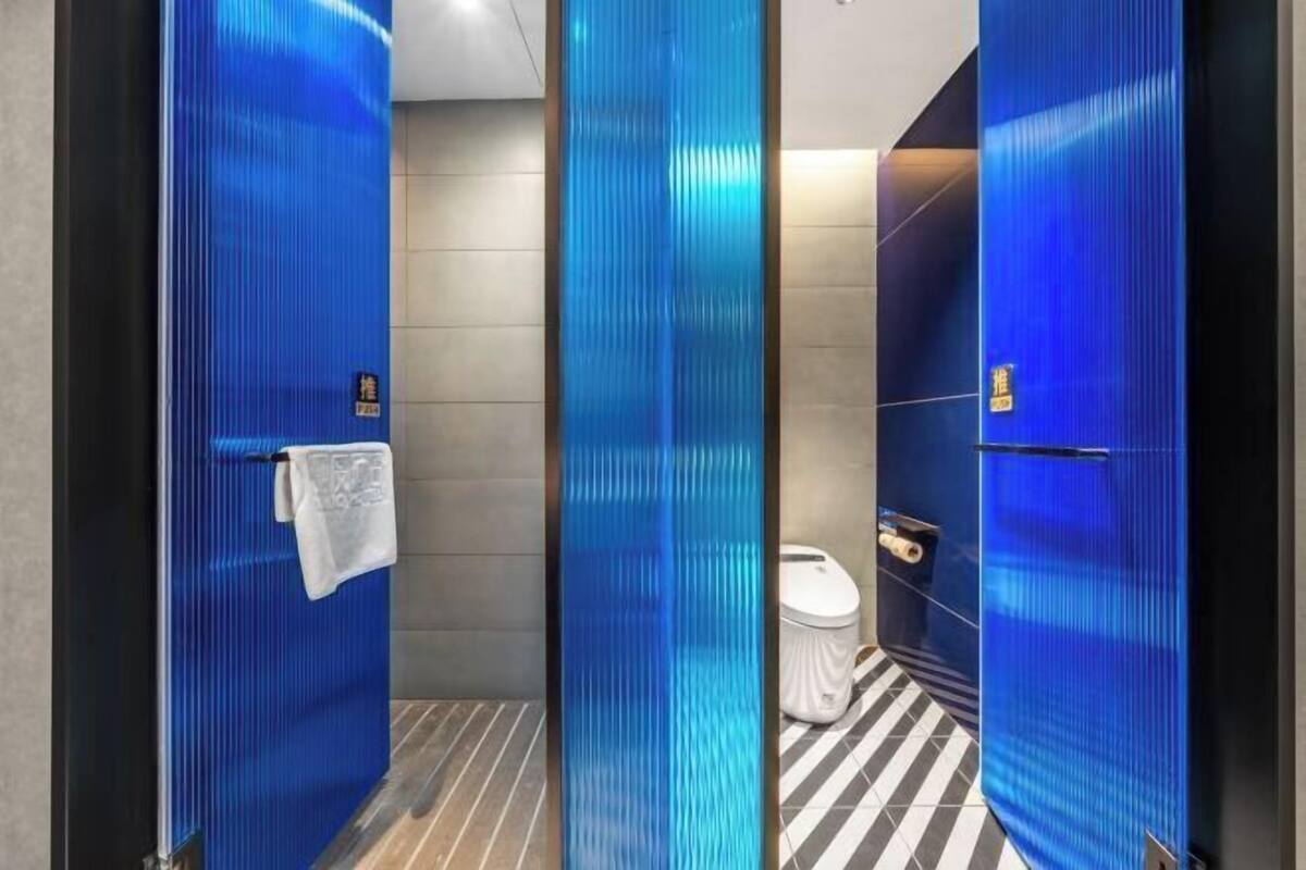 A modern bathroom with a blue glass partition, a towel rack, and a toilet.