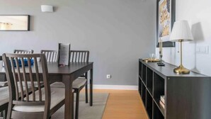 A dining area with a wooden table and chairs, a black console table with a lamp, and a framed picture on the wall.